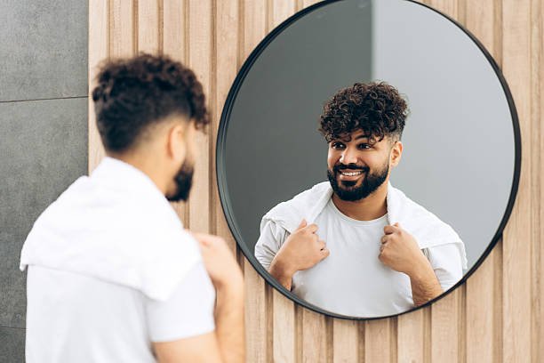 istock Confident middle eastern man smiling in bathroom mirror reflecting self-care in modern bathroom 2253531153