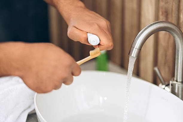 istock Man preparing to brush teeth with bamboo toothbrush and toothpaste selective focus on hands 2253531163
