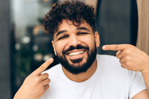 istock Happy smiling middle eastern man pointing at his white healthy teeth looking at camera 2253531186