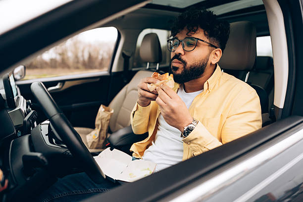 istock Attractive, handsome man eating fast food burger in car 2253531190