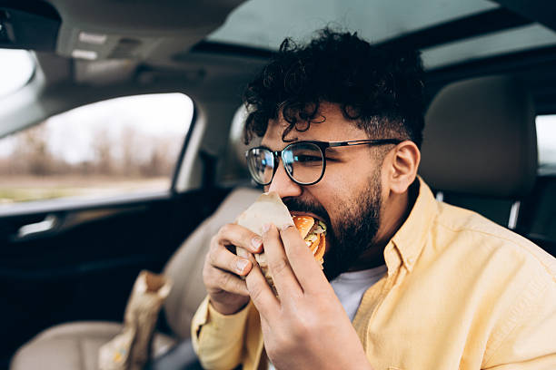 istock Middle eastern man eating fast food burger in car 2253531192