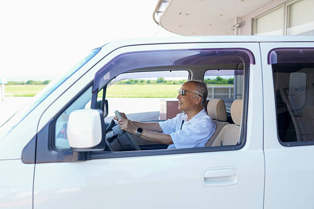 A man in a white shirt is driving a white van. He is smiling and he is enjoying the ride