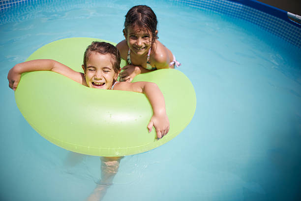 Two cheerful girls enjoying summer fun in a swimming pool with a bright green float
