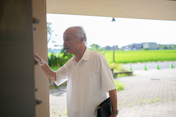 An older man is standing outside a building, holding a briefcase. The scene is quiet and peaceful, with a sense of calmness and serenity