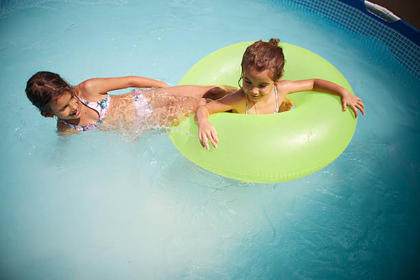 Two happy girls enjoying summer fun in a swimming pool with an inflatable ring
