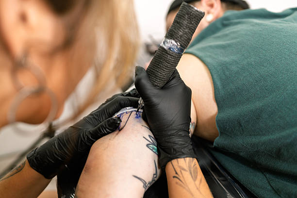 istock Tattoo artist working on client arm in studio 2253538501