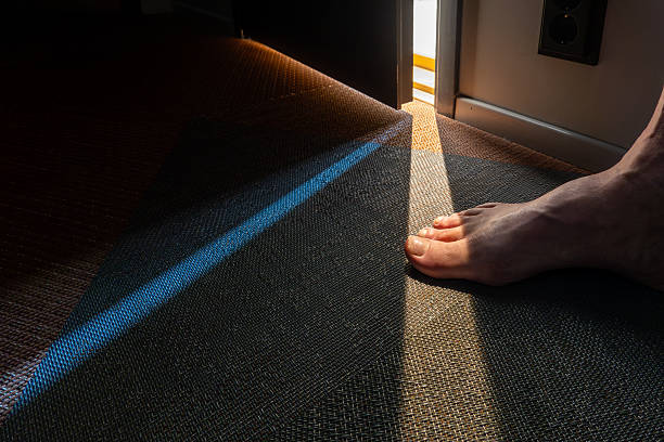 Tallinn, Estonia A man's foot and toes illuminated by the crack of a door on the floor.