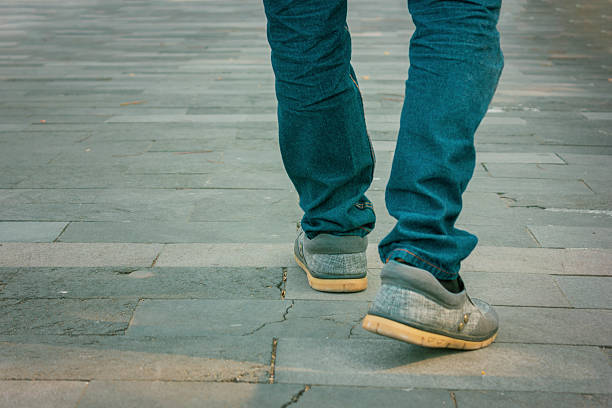 Man wearing sneakers and blue denim  on paving block