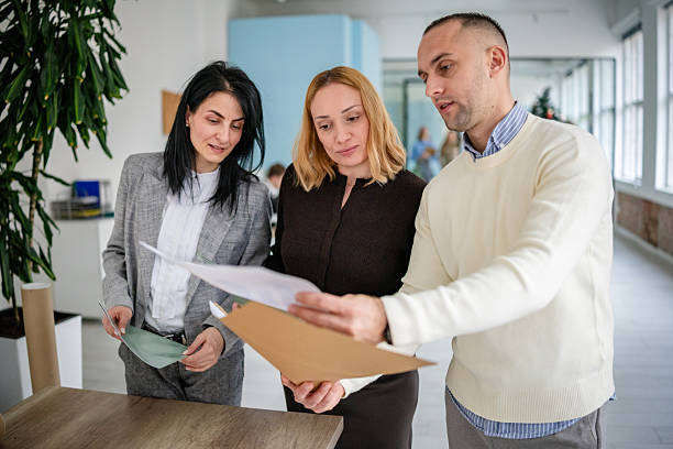 istock Adults working together in an office discussing documents during business hours with colleagues 2253541619
