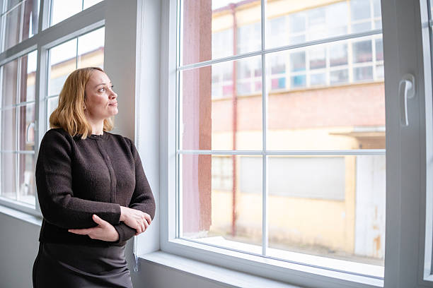 istock Woman looks out of office window while engaged in thoughts about work and projects during the day 2253545769