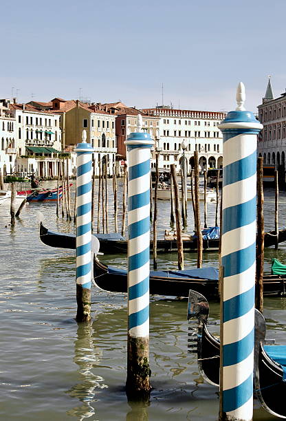 Blue and white poles and gondolas on the grand canal of Venice.