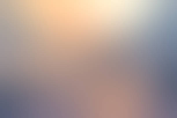 istock Soft, defocused abstract gradient background blending warm peach and gold tones into cool muted blue and grey shadow. 2253547529