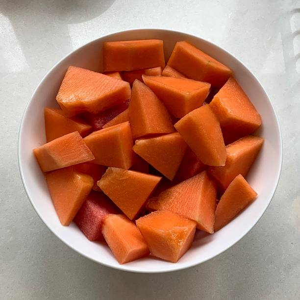 Fresh melon cubes neatly arranged in a bowl, showcasing their vibrant orange and green hues. A refreshing and visually appealing treat, perfect for any occasion.