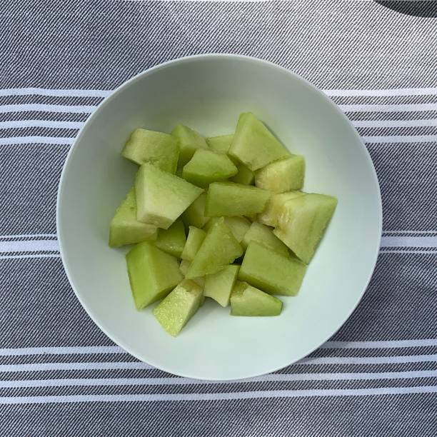 Fresh melon cubes neatly arranged in a bowl, showcasing their vibrant orange and green hues. A refreshing and visually appealing treat, perfect for any occasion.