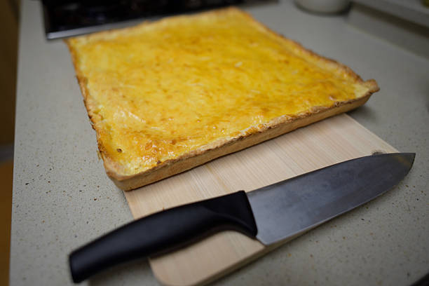 A freshly baked Georgian Khachapuri cheese pie on a wooden cutting board with a knife beside it