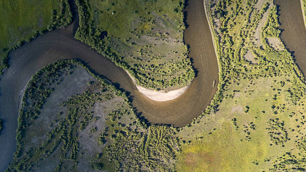 istock Aerial view of meandering river surrounded by lush greenery featuring mountain valley forest road sky cloud sunlight rock and hiking 2253551954