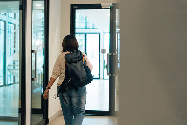 istock Woman with backpack walking through modern building corridor transitioning spaces 2253553183