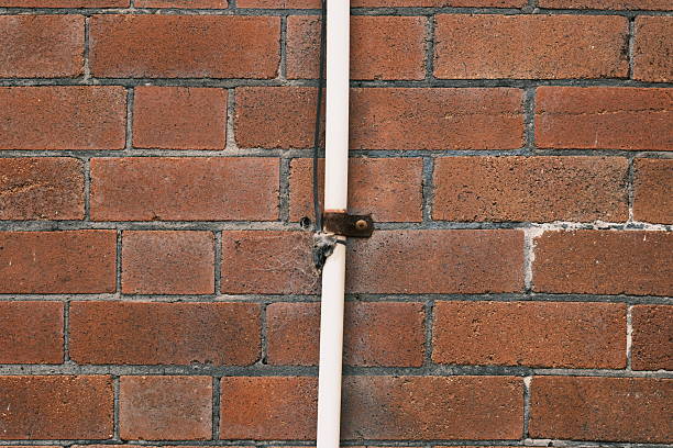 Close-up on an old brick wall with a white plastic pipe