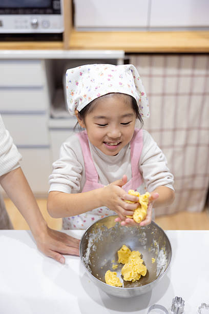 Little girl kneading cookie dough in kitchen
