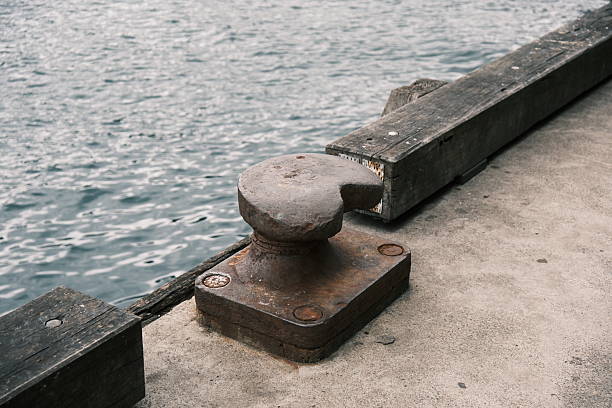 Old rusty metal mooring bollard on a pier by the sea.