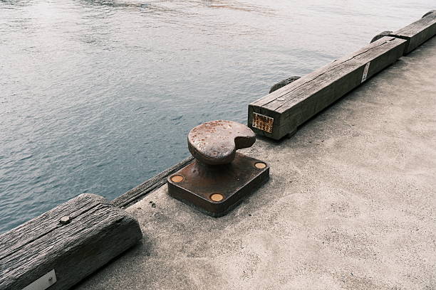 Old rusty metal mooring bollard on a pier by the sea.