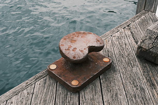 Old rusty metal mooring bollard on a pier by the sea.