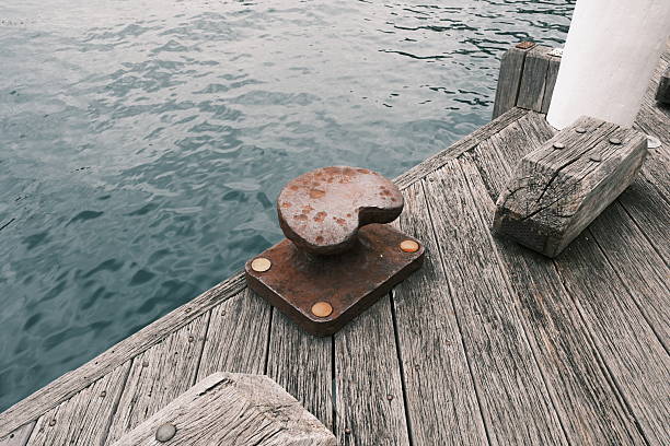 Metal bollard for boats and vessels on wharf over sea and sunset background close up. Maritime quayside with equipment for yatching at coastline. Travel season.
