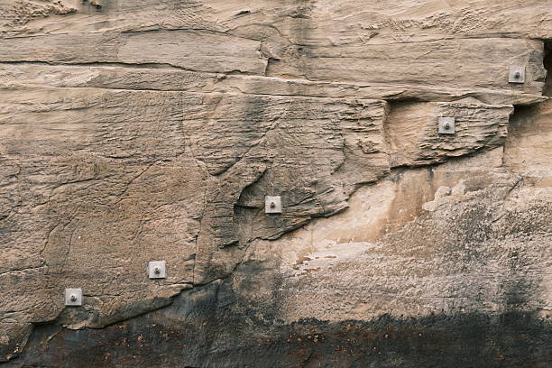Metal bolts over a large crack in a rock wall to stop it collapsing.