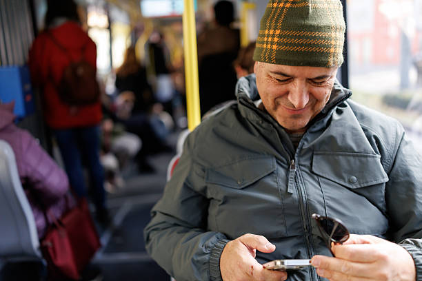 Mature man using smart phone while traveling by bus during cold winter day