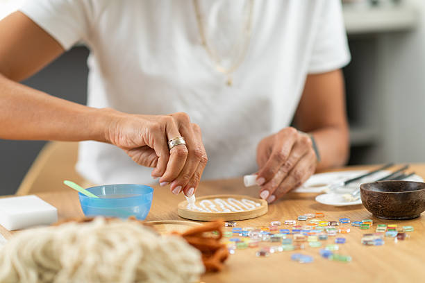 Applying glue to secure coaster layers in a home craft session. Captures careful bonding, precision, and step by step artistic assembly.