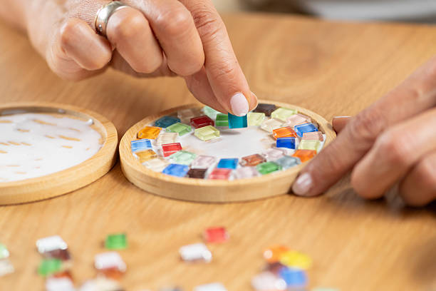 istock Woman assembling coasters by gluing small decorative parts during a home craft session. Highlights precision, hand coordination, and detailed creative work. 2253558813