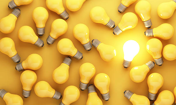 istock Innovation concept with one glowing light bulb among many identical bulbs on yellow background symbolizing breakthrough idea creativity and problem solving 3d rendering 2253559277