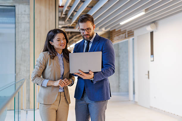 istock Business professionals collaborating on laptop in modern office hallway 2253559347