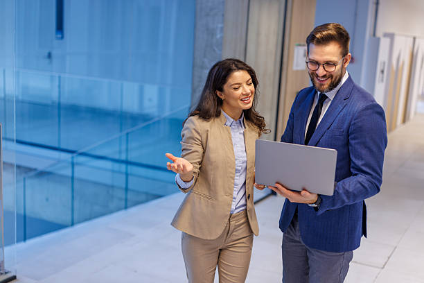 istock Business professionals collaborating using laptop in modern office hallway 2253559348