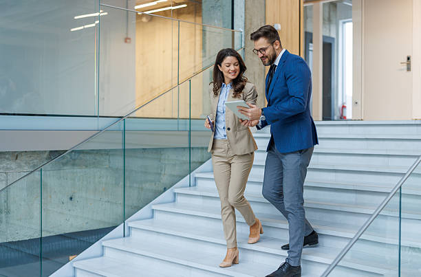 istock Business colleagues collaborating on digital tablet walking downstairs 2253559389