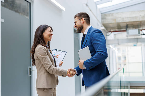 istock Business people shaking hands in modern office hallway 2253559433