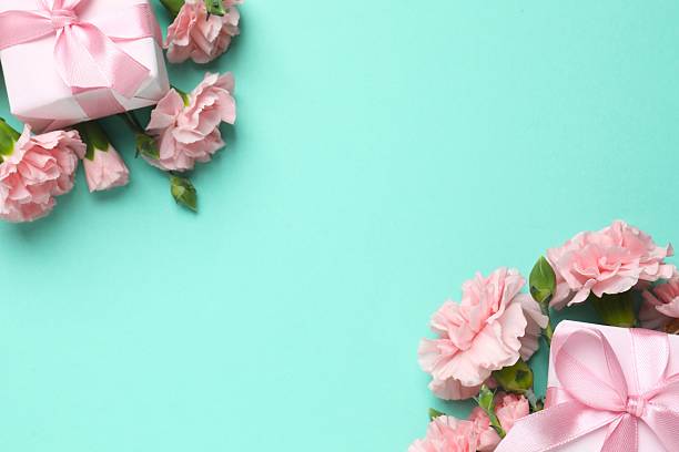 istock Beautiful bouquet of pink carnations with gift boxes on a colored background 2253561052