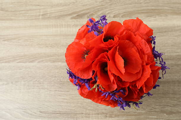 Beautiful bouquet with red poppies on wooden background