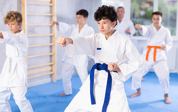istock Preteen attendee of karate classes practicing kata standing in row with others 2253566670
