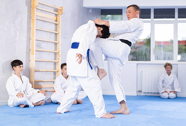 istock Karate sensei demonstrating fighting techniques to disciples during kumite with boy 2253566719