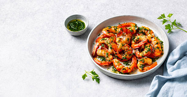 istock Grilled shrimps with chimichurri sauce on a white plate. Grey background. Copy space. 2253571375
