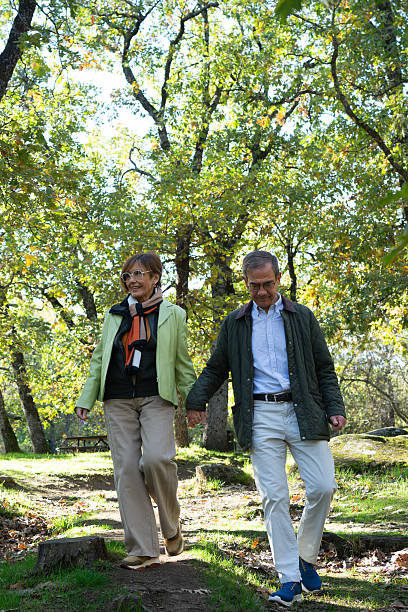 istock Senior couple holding hands walking in nature park 2253574064