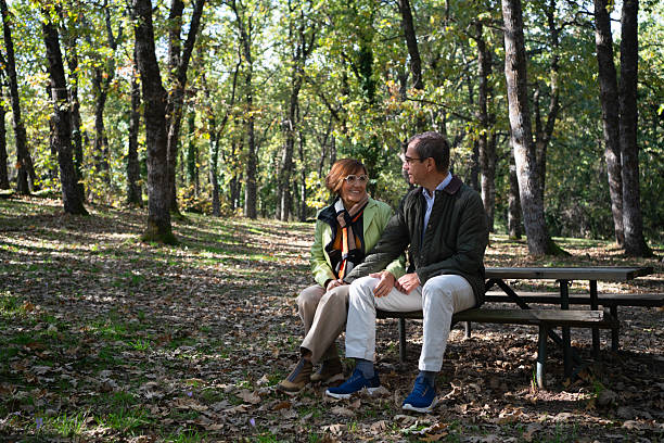 istock Senior couple enjoying conversation on park bench during autumn 2253574074