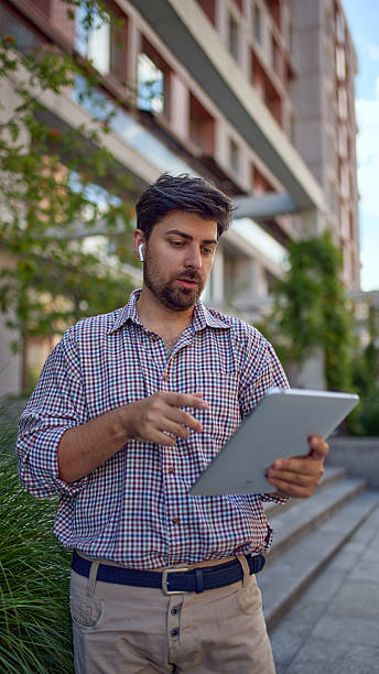 istock Businessman standing outdoors using tablet with wireless earphones 2253574242