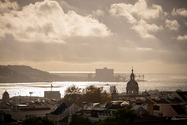 Lisbon Portugal December 07 2025. Evening light reflects on the Tagus River behind historic rooftops and church domes.