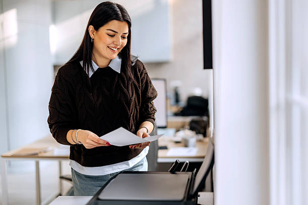 istock Young businesswoman using printer at the office 2253578383