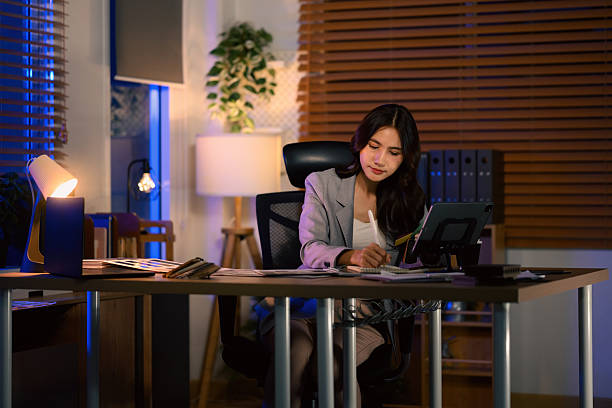 istock Asian interior designer working late at night, sketching ideas at her desk under warm lamp light in a modern office 2253579686