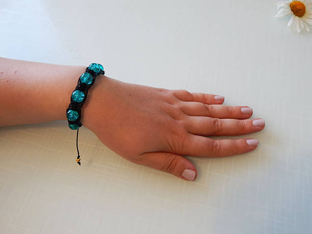 istock Hand-knotted turquoise bracelet on a wrist 2253581064