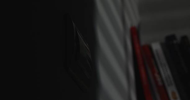 istock Light switch on the wall in the dark, blurred books in the background. 2253584562