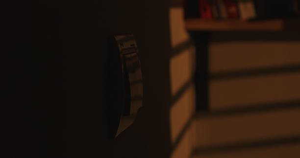 istock Light switch on the wall in warm yellow sunset light, blurred books in the background. 2253586089